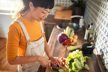 Asian woman chopping vegetables in kitchen for healthy meal prep