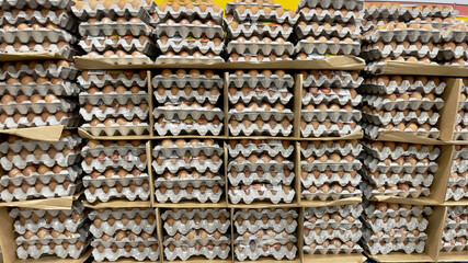 Many cardboard trays of chicken eggs stacked for sale in a supermarket display