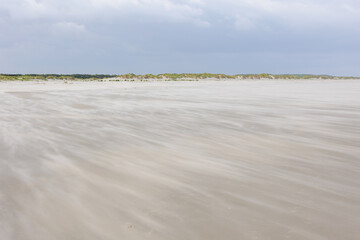 Landscape view of wide and long sand beach on the Dutch Wadden sea under cloudy sky, Schiermonnikoog is a municipality and national park in the Northern Netherlands and one of the West Frisian Islands