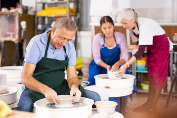 Old man create pottery sculpture with hands on a pottery wheel from grey clay