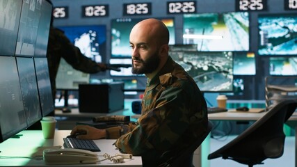 Man looking at screens in military HQ base housing operational missile defense system designed to intercept ballistic rockets. Special forces expert using tracking gear and radar systems, camera A