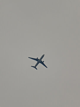 jetliner flying under a gray sky.