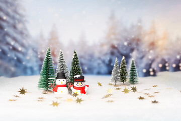 Two snowmen are standing in the snow next to a row of trees, Christmas and New Year banner.