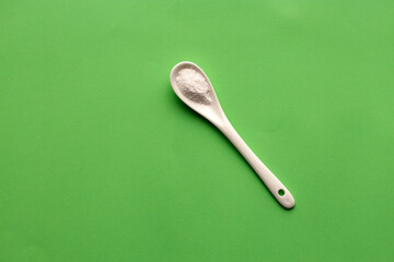 Baking soda powder in spoon - Healthy food. Green background