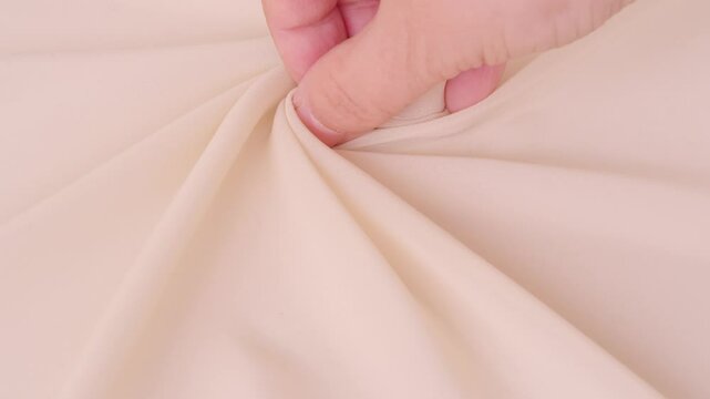 Female hands inspecting silk texture and quality delicate chiffon, crepe, hand feels sensual tactile pleasure, testing for durability, stretch and crease resistance