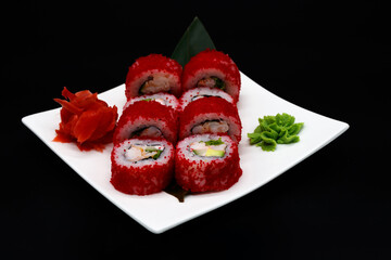 Prepared sushi rolls on a white plate on a black background
