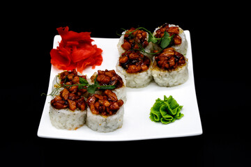 Prepared sushi rolls on a white plate on a black background