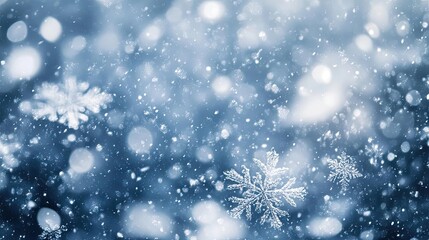 Fototapeta premium Delicate snowflakes gently fall against a blurred winter background, creating a serene and magical atmosphere of snowfall.