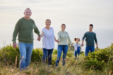 Big family, portrait and holding hands with child in nature for outdoor adventure, holiday and bonding. Happy, parents and grandparents with little girl at field for vacation, care and weekend trip