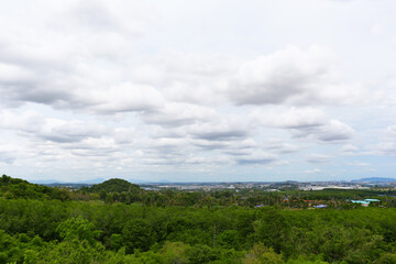 Green forest view and looking at Pinthong 3 Industrial Estate located in Sriracha District, Chonburi Province, with the sky and white clouds as the background.