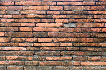 Surface of the red brick wall is old, dirty and covered with black mold.