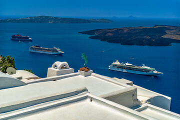 Fototapeta premium Early morning view of Fira bay on Santorini island, Greece. White roofs, seahorse statue, Nea Kameni, and the luxury cruise ships in the bay