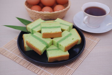 pandan cake on a black plate with cup of tea. beautiful decoration
