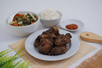 black pepper chicken meat in white plate with rice and vegetables in a bowl on bamboo mat.