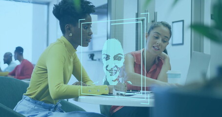 Facial recognition image over diverse colleagues discussing work at desk