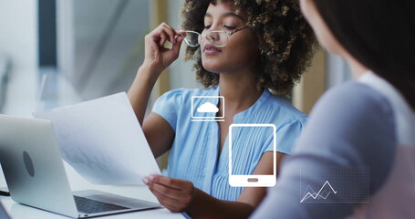 Image of financial data processing with icons over diverse colleagues discussing work in office