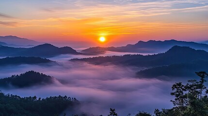 Fototapeta premium A stunning sunrise over misty mountains, casting warm hues on a serene landscape, perfect for nature lovers and outdoor enthusiasts.