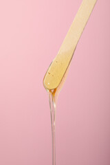 A wooden stick for depilation on a pink background