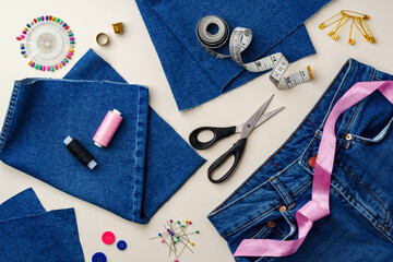 Sewing supplies and denim fabric arranged on a workspace for clothing alterations in a bright...