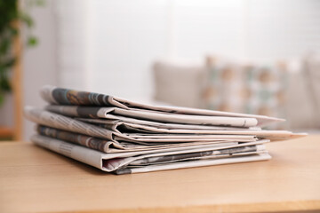 Stack of newspapers in different languages on table indoors