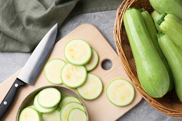 Fresh zucchinis and knife on grey textured table, flat lay