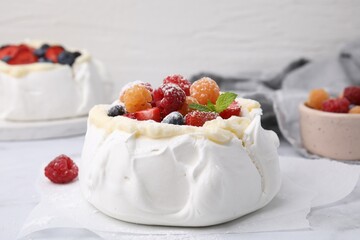 Pavlova cake (meringue dessert) with whipped cream, fresh berries, powdered sugar and mint on table, closeup