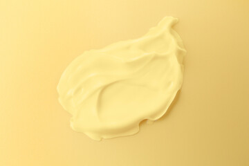 Sample of face cream on yellow background, top view