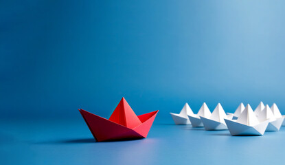 A group of white paper boats led by a red paper boat, Red paper boat leading white boats on a blue background, Business leadership concept