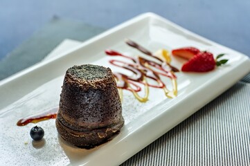 A dessert featuring a chocolate lava cake with fruit garnishes and sauces.
