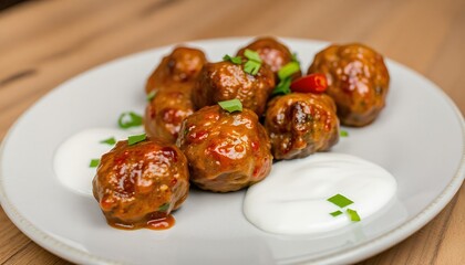 plate of spicy lamb meatballs with a side of yogurt sauce.