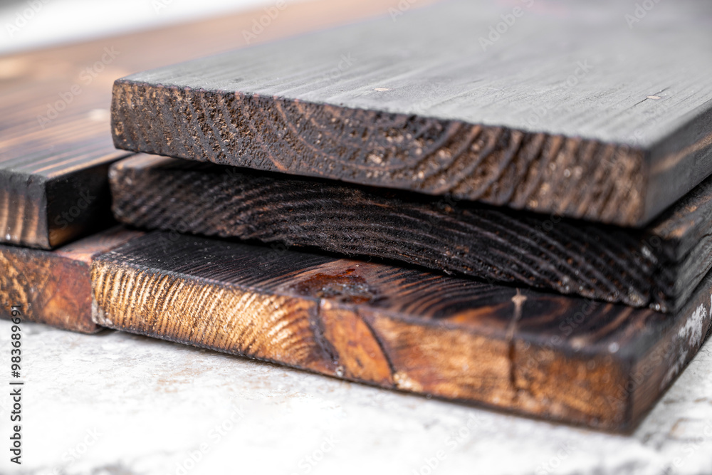 Poster a stack of wood planks with a burnt look. the wood planks are stacked on top of each other, creating