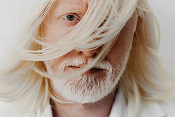 Portrait of a man with long white hair and a beard, showcasing his intense gaze against a soft...