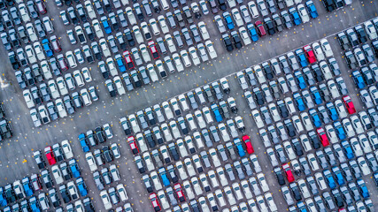 Fototapeta premium Aerial view new cars lined up in the port for import and export, Top view of new cars lined up automobile factory global logistic import export, New cars logistic to dealership for sale.