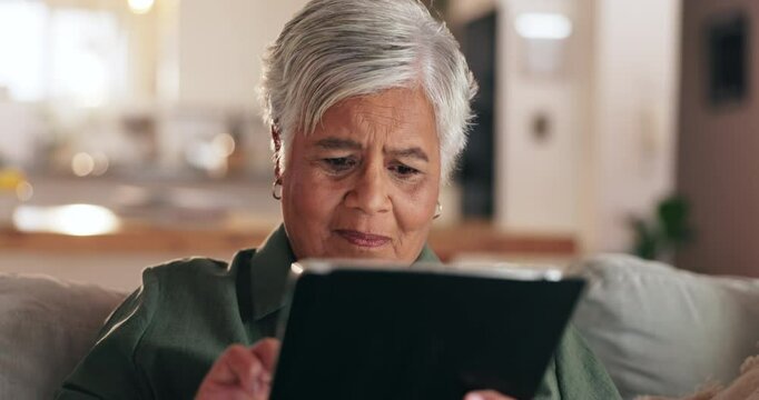Senior woman, tablet and reading on sofa, texting and thinking with application for contact in home. Person, touchscreen and scroll for movie, ebook and social network with subscription in retirement