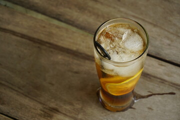 Refreshing iced drinks with lemon slices on a wooden table outdoors. Summer beverage concept.