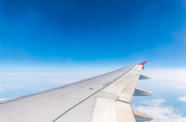 Fototapeta premium View from the airplane window at a beautiful cloudy sky and the airplane wing