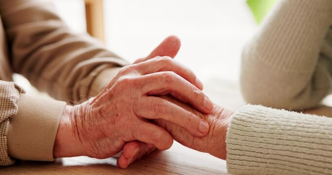 Holding hands, love and elderly couple by table for support, sympathy or condolences for loss. Unity, home and senior man and woman with connection for trust, commitment and care in marriage bonding.