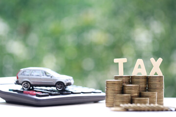 Car tax concept, Stack of coins money with tax wooden text and miniature car model on natural green background, Saving money for car, Finance and car loan