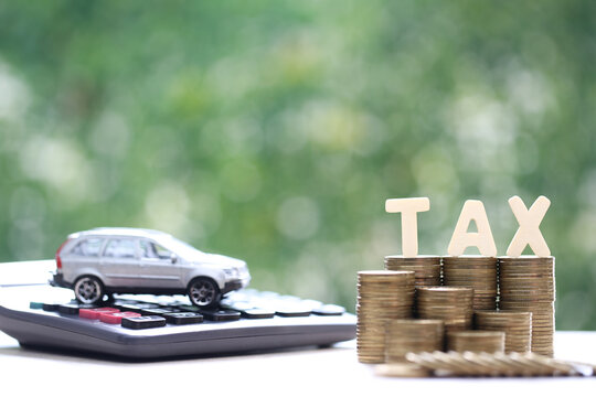 Car tax concept, Stack of coins money with tax wooden text and miniature car model on natural green background, Saving money for car, Finance and car loan