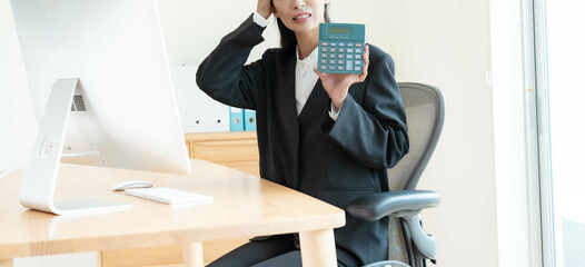 電卓を持ち頭を抱えるスーツを着た女性