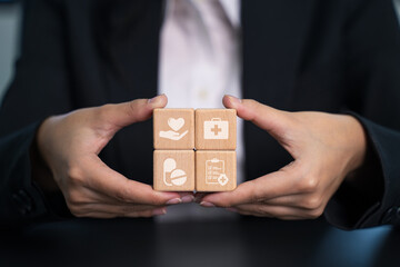  Woman's hand arrange  shape with clinic or hospital sign on wooden cube block . Wellbeing, World Health Day concept