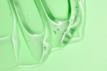 Squeezed cosmetic clear cream gel texture Isolated on green background. Close up transparent aloe...