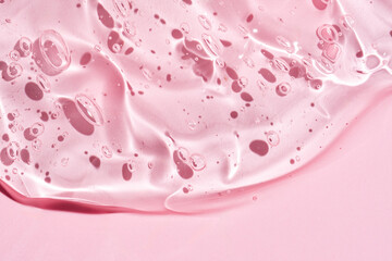Gel serum texture background. pink skin care liquid swirl. Clear cosmetic cream with bubbles closeup on pink