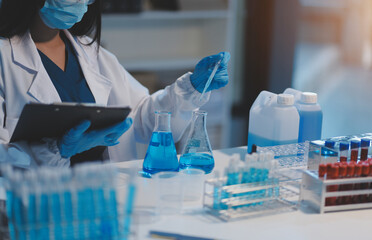 Fototapeta premium Group of dedicated scientist conduct chemical experiment in medical laboratory, carefully drop precise amount of liquid from pipette into test tube for vaccine drug or antibiotic development. Neoteric