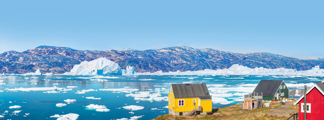 Panoramic view of colorful Kulusuk village in East Greenland - Kulusuk, Greenland - Melting of a iceberg and pouring water into the sea © muratart