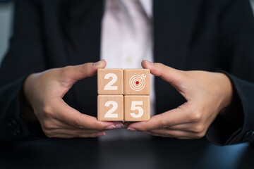 New year goal and plans.  Woman's hand holding wood block goals for New Year.  Businesswoman protecting increasing investment with 2025 financial goal