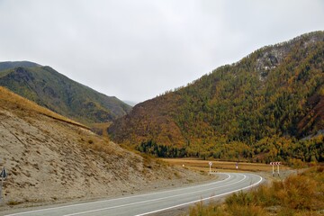A winding road through a mountainous landscape with autumn foliage.