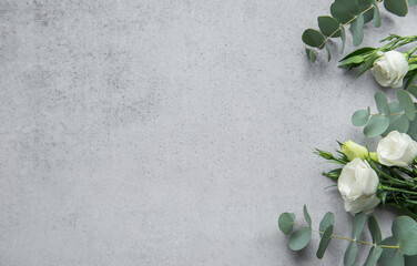 Delicate arrangement of mixed  flowers and eucalyptus leaves on a light grey surface
