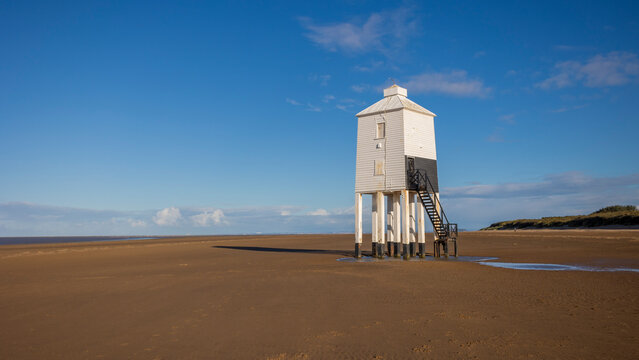 The low lighthouse at Burnham on Sea. taken as the tide is out with a blue sky and deserted beach. It was built in 1832