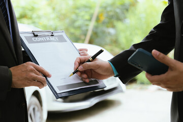 Car rental dealer is signing a rental contract with a professional salesperson. The agent will explain the details about car insurance and maintenance to ensure a smooth rental and service process.
